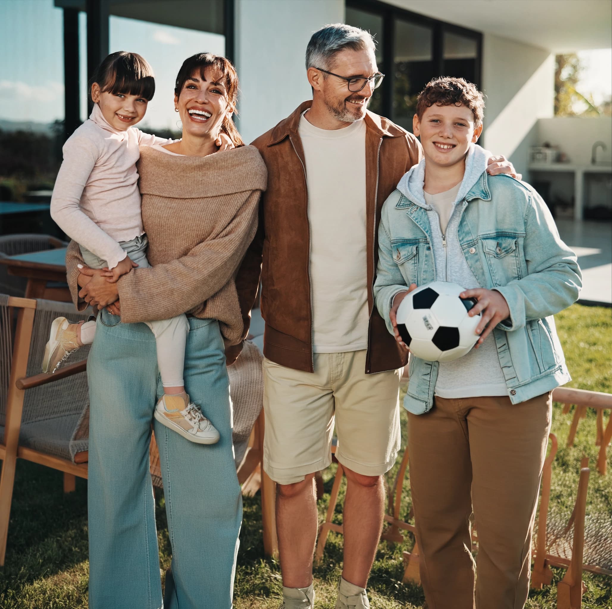 A family of four with a soccer ball outside their home